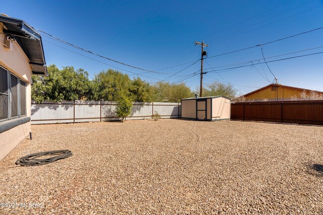 view of yard with an outbuilding, a storage unit, and a fenced backyard