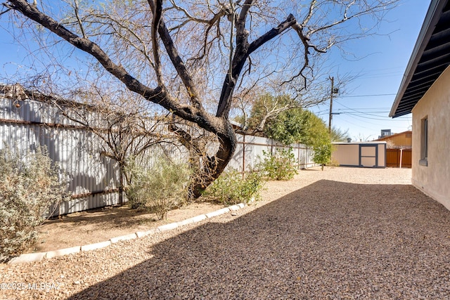 view of yard with a patio area, a fenced backyard, a storage unit, and an outbuilding