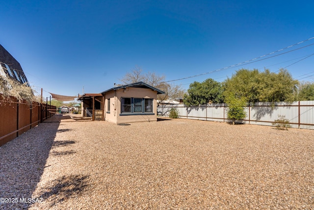 rear view of property with a fenced backyard and stucco siding