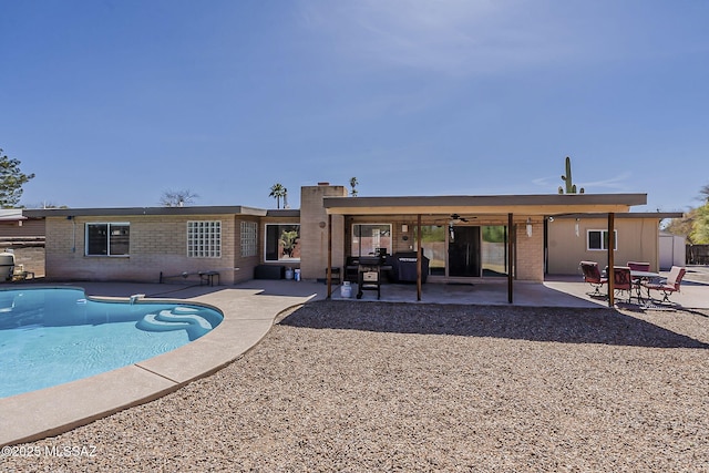 back of property featuring an outdoor pool, a patio area, brick siding, and fence