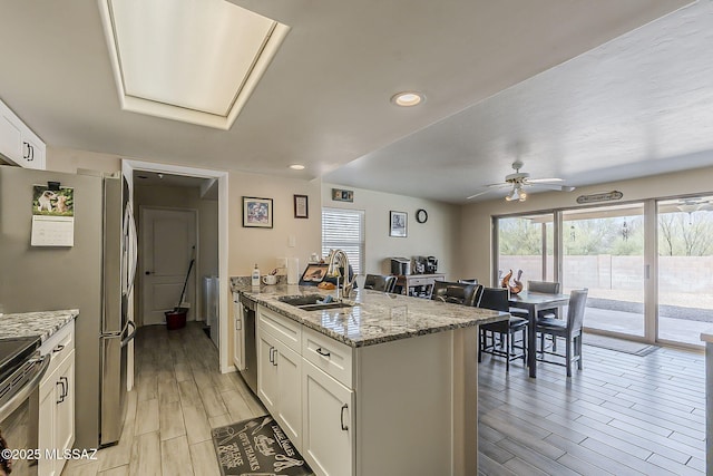 kitchen with a peninsula, white cabinets, stainless steel appliances, and a sink