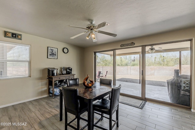 dining space featuring ceiling fan, a textured ceiling, baseboards, and wood finished floors