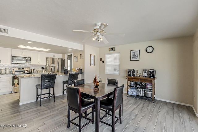 dining area featuring a ceiling fan, light wood-type flooring, visible vents, and baseboards