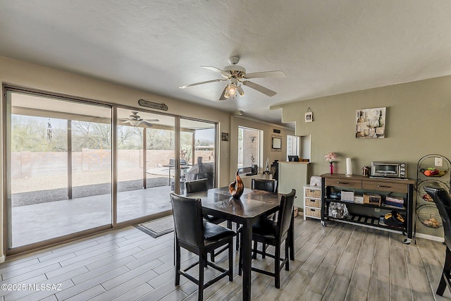 dining room with light wood finished floors, ceiling fan, and a textured ceiling