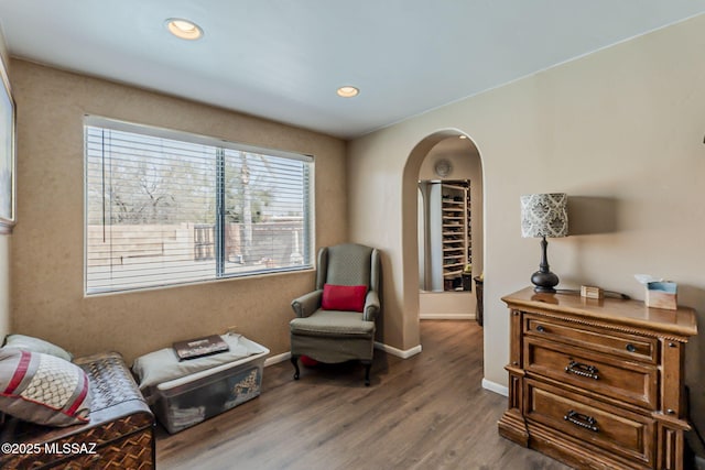 sitting room with arched walkways, recessed lighting, wood finished floors, and baseboards