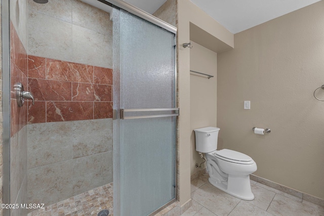 bathroom featuring a shower stall, toilet, and baseboards