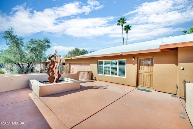 view of front of property with a patio area, fence, and stucco siding