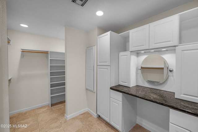 interior space featuring visible vents, white cabinets, baseboards, dark stone counters, and recessed lighting