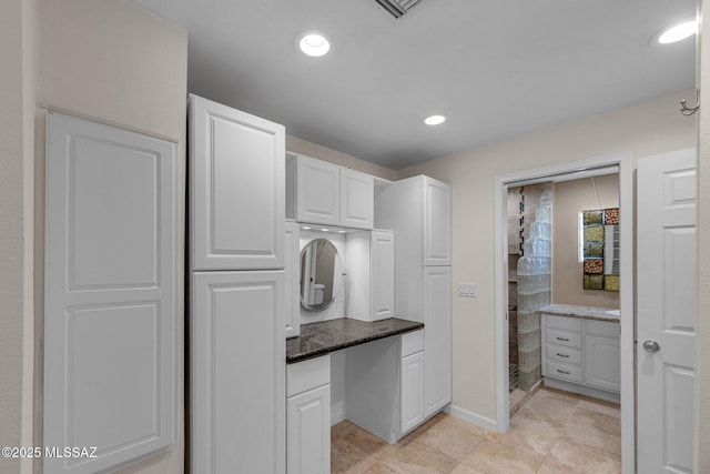 kitchen featuring dark stone counters, recessed lighting, baseboards, and white cabinets