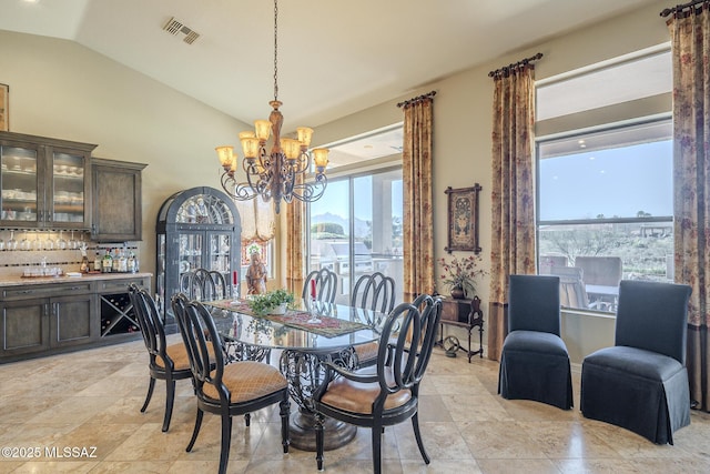 dining area with vaulted ceiling, a dry bar, visible vents, and an inviting chandelier