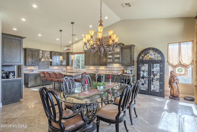 dining room featuring baseboards, visible vents, a chandelier, wine cooler, and high vaulted ceiling