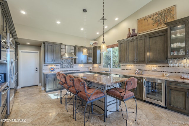 kitchen featuring wine cooler, a sink, visible vents, wall chimney exhaust hood, and decorative light fixtures