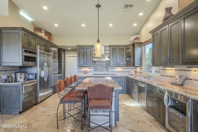 kitchen with visible vents, wine cooler, appliances with stainless steel finishes, light stone countertops, and a sink