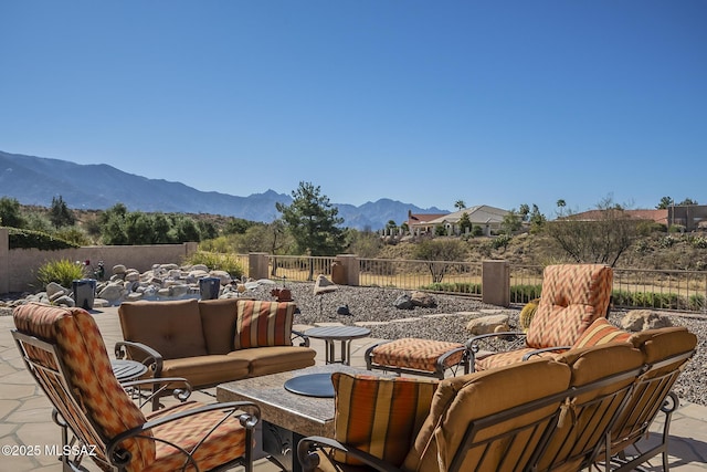 view of patio with outdoor lounge area, a mountain view, and fence