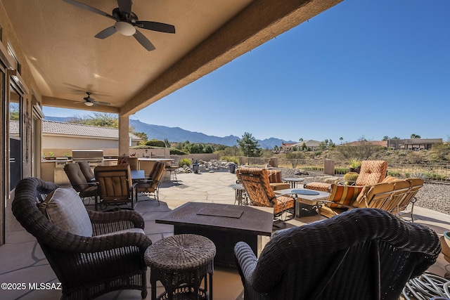 view of patio / terrace with outdoor dining space, an outdoor kitchen, a mountain view, and a ceiling fan