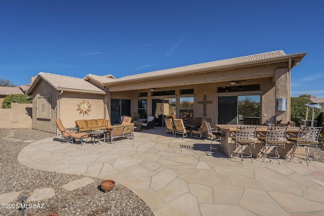 rear view of property featuring a ceiling fan, an outdoor hangout area, a tiled roof, a patio area, and stucco siding