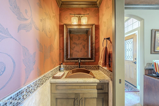 bathroom featuring ornamental molding, vanity, and wallpapered walls