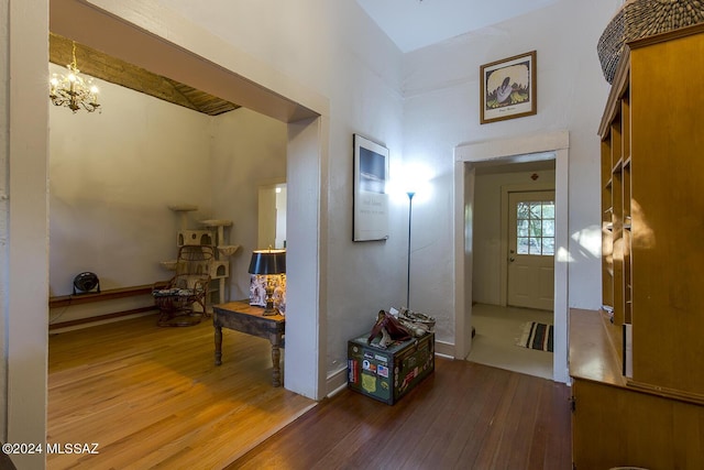 hallway with hardwood / wood-style floors and an inviting chandelier