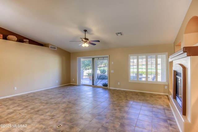 unfurnished living room with tile patterned floors, visible vents, vaulted ceiling, and a glass covered fireplace