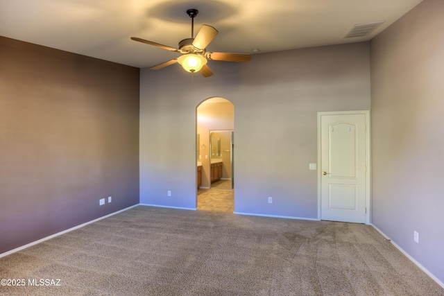 interior space featuring baseboards, visible vents, arched walkways, and a ceiling fan