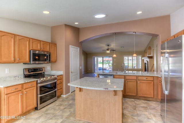 kitchen with arched walkways, light stone counters, stainless steel appliances, a peninsula, and a sink