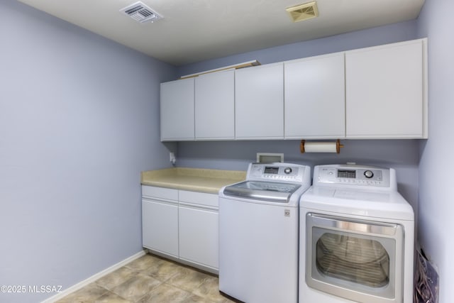 clothes washing area with separate washer and dryer, cabinet space, visible vents, and baseboards