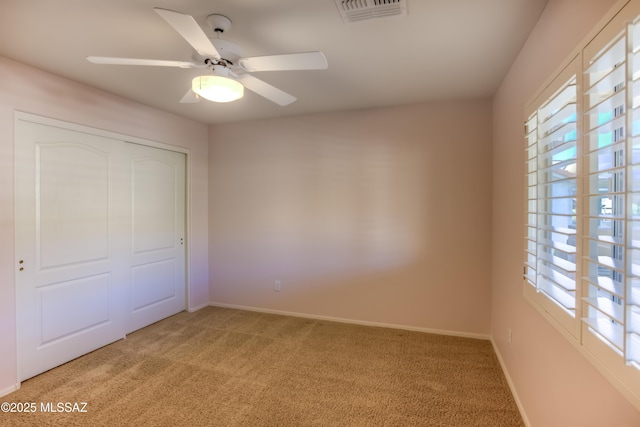 unfurnished bedroom featuring light carpet, baseboards, visible vents, ceiling fan, and a closet