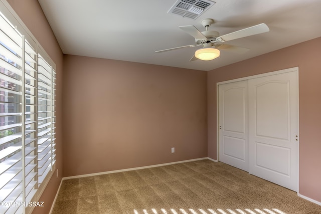 unfurnished bedroom with a closet, visible vents, a ceiling fan, carpet flooring, and baseboards