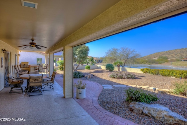 view of patio / terrace with outdoor dining area, a water view, visible vents, a ceiling fan, and fence