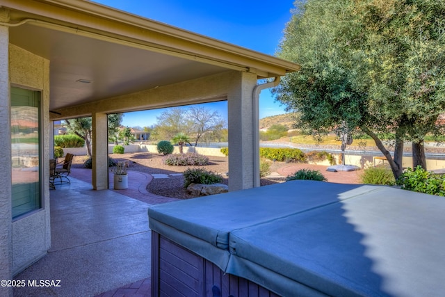 view of patio / terrace featuring fence and a hot tub