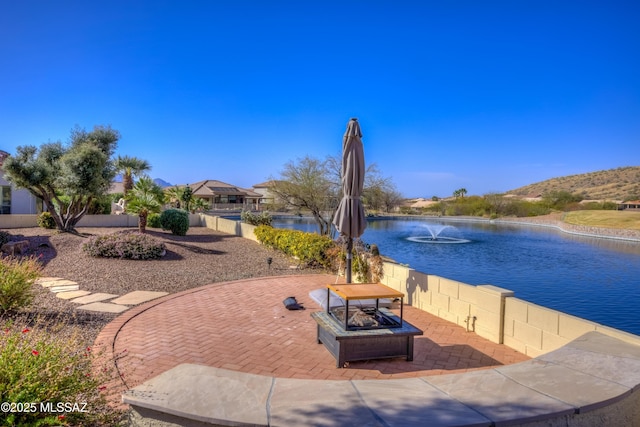 view of property's community with a water view, an outdoor fire pit, and a patio