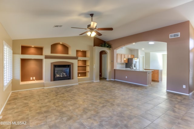 unfurnished living room featuring built in shelves, lofted ceiling, visible vents, and ceiling fan