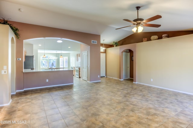 empty room featuring lofted ceiling, ceiling fan, arched walkways, a sink, and visible vents