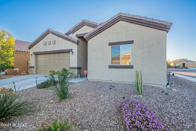 view of front facade featuring stucco siding, concrete driveway, an attached garage, and a tiled roof