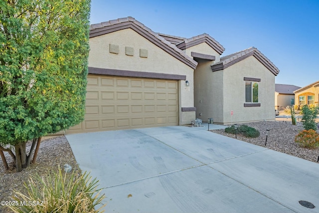 view of front of home featuring stucco siding, a garage, concrete driveway, and a tiled roof