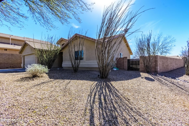 single story home with a tile roof, stucco siding, a gate, fence, and a garage