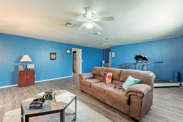 living room featuring a ceiling fan, baseboards, visible vents, and wood finished floors