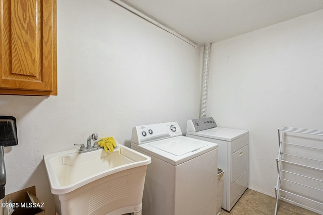 clothes washing area with cabinet space, a sink, and washer and clothes dryer