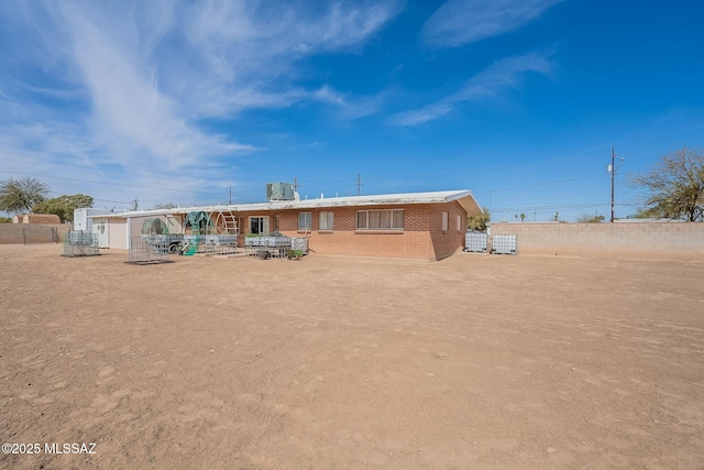 rear view of property featuring fence, central AC, and brick siding