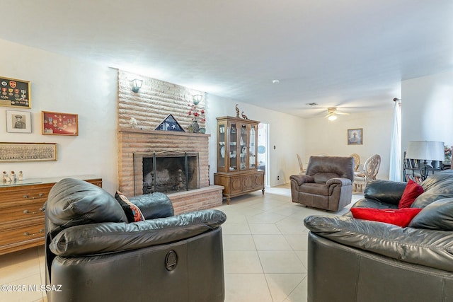 living area with a brick fireplace, ceiling fan, and light tile patterned flooring