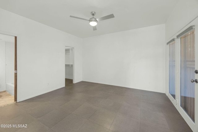 unfurnished bedroom with ceiling fan, a closet, a walk in closet, and baseboards