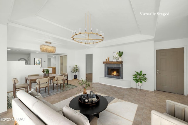 tiled living area with a tray ceiling, a tile fireplace, and an inviting chandelier