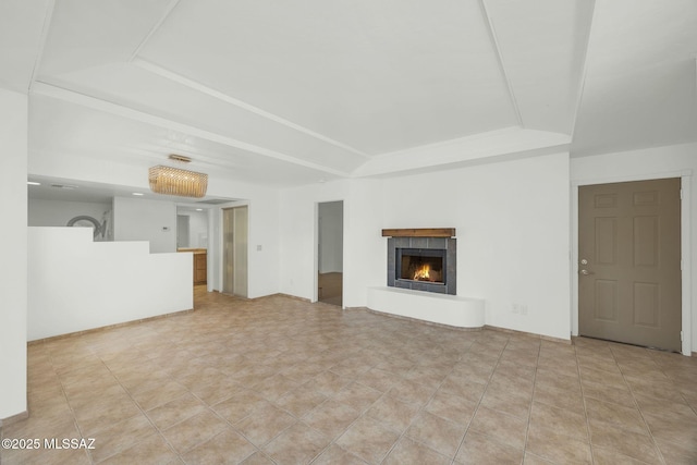 unfurnished living room featuring a fireplace, a raised ceiling, and tile patterned floors