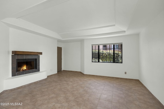 unfurnished living room featuring a tray ceiling, a tiled fireplace, and tile patterned flooring