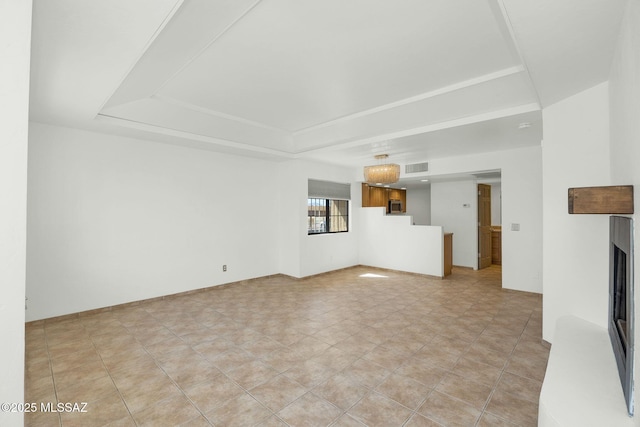 unfurnished living room with a tray ceiling, a fireplace, and visible vents