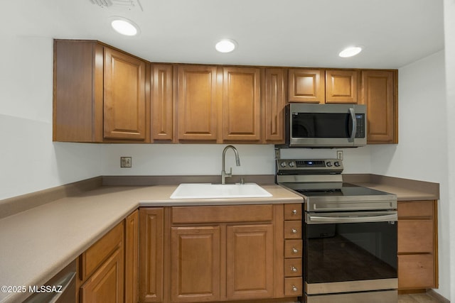 kitchen featuring stainless steel appliances, recessed lighting, light countertops, brown cabinetry, and a sink