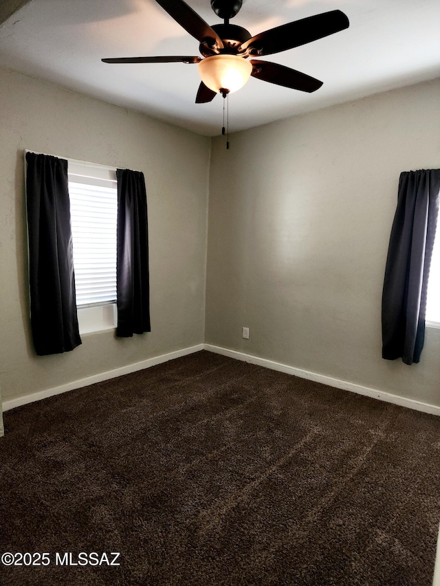 carpeted spare room with ceiling fan and baseboards