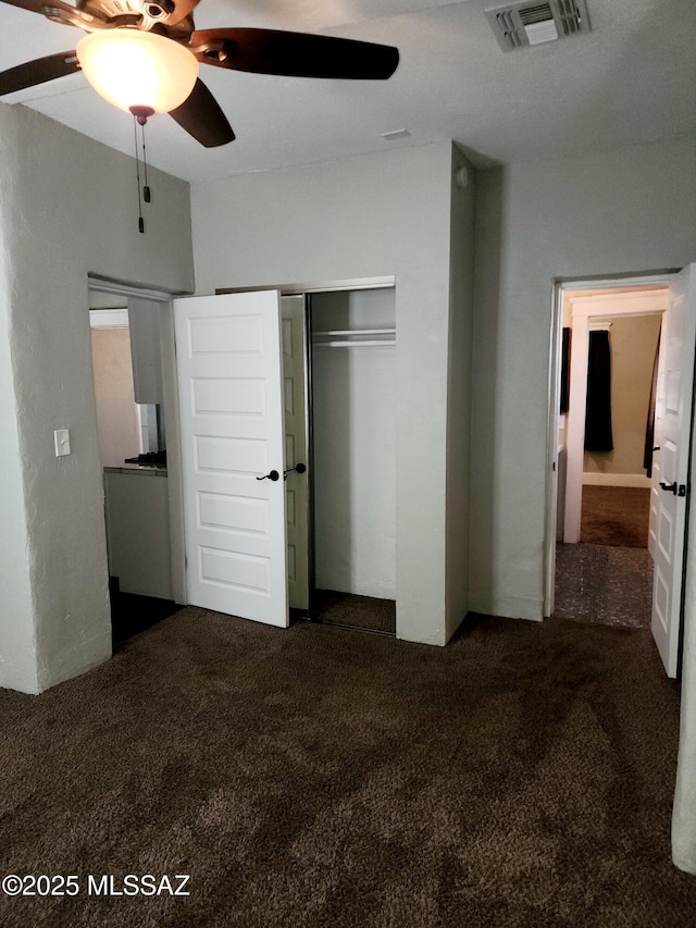 unfurnished bedroom featuring a closet, carpet flooring, visible vents, and a ceiling fan