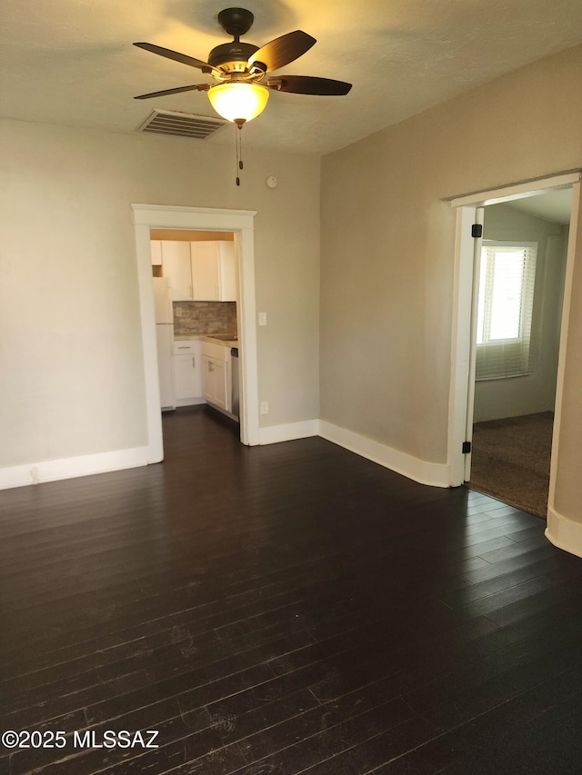 empty room featuring dark wood-style floors, visible vents, baseboards, and a ceiling fan