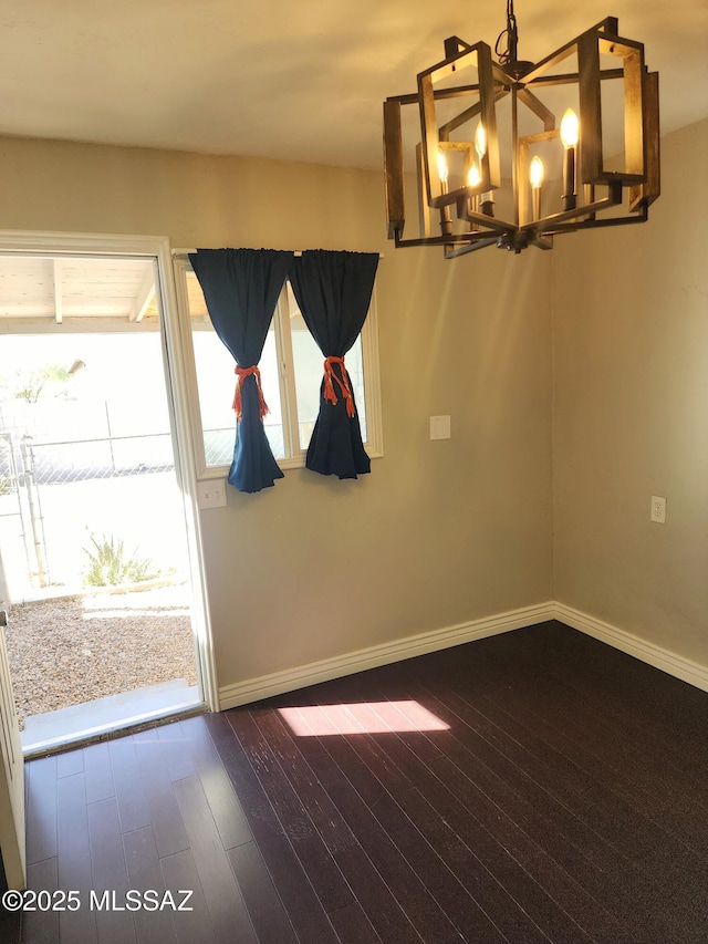 interior space featuring dark wood-style flooring, baseboards, and an inviting chandelier